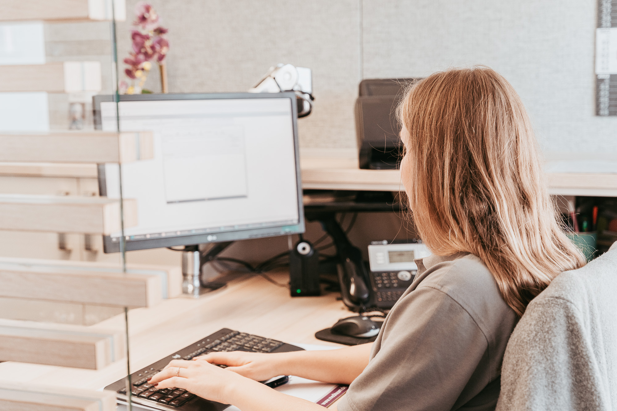 Eine Person sitzt am Schreibtisch und arbeitet am Computer.