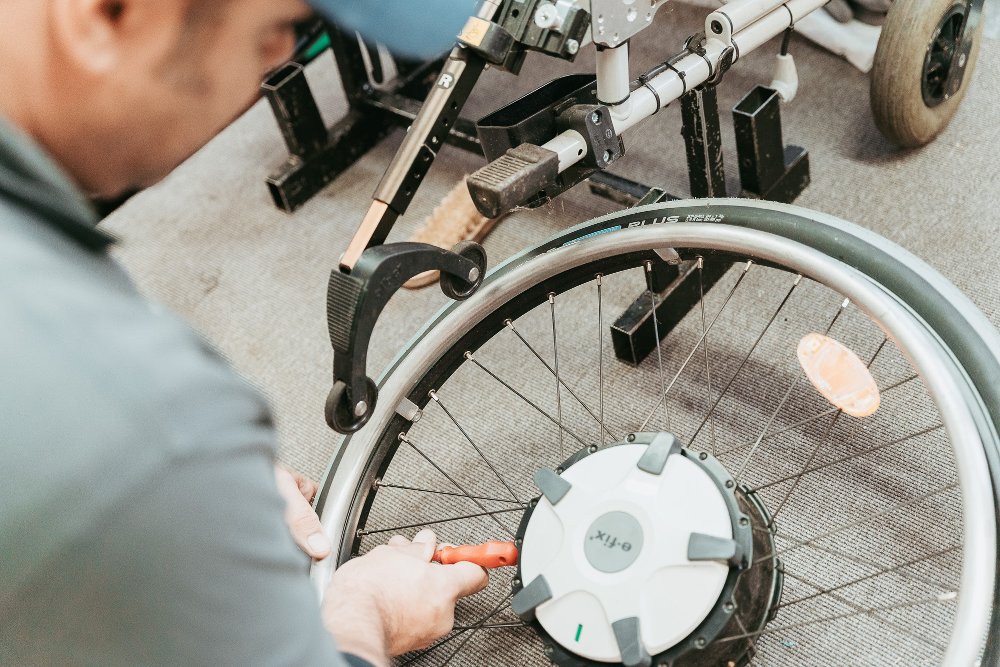 Ein Techniker repariert ein Rollstuhl-Rad mit einem Schraubenschl&uuml;ssel.